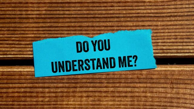 Do you understand me message writing on ripped torn blue paper piece on wooden background