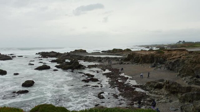 People walking on the Glass Beach on a cloudy rainy day in Fort Bragg, California, USA