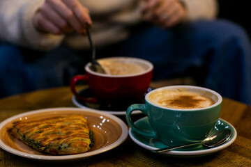 cup of coffee with spinach pie close up photo with human hand. High quality photo