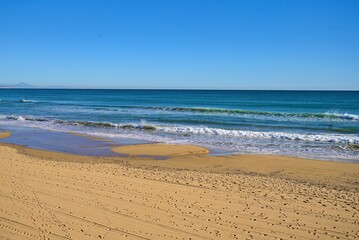 Beaches of Costa Blanca with gentle waves and clear sky.