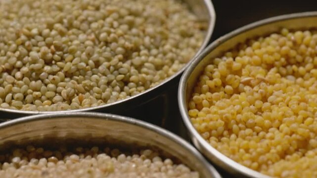 Different types of millets in stored in steel bowls, 4k, close up, push in shot