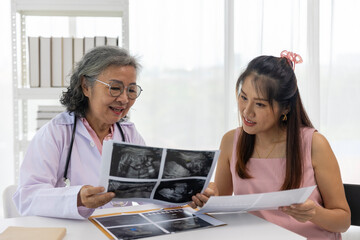Senior female Doctor Discussing Ultrasound Results with Pregnant Woman