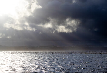 People in silhouette walking around coastal marine lake in stormy weather 