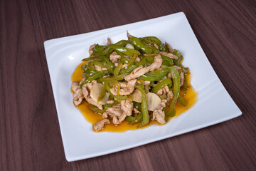 Shredded pork with green pepper on a white plate on the table