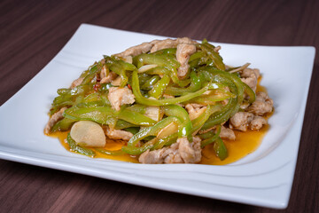 Shredded pork with green pepper on a white plate on the table