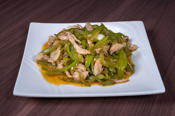 Shredded pork with green pepper on a white plate on the table