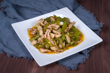 Shredded pork with green pepper on a white plate on the table