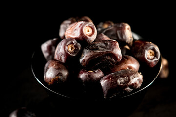 Dried dates displayed on a dark plate highlighting their rich texture and natural sweetness