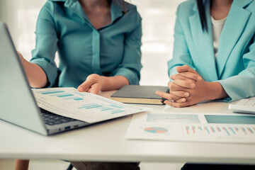 Fototapeta premium Two Asian women are reviewing financial transaction documents and calculating expenses with a business idea calculator to increase profits and business strength.