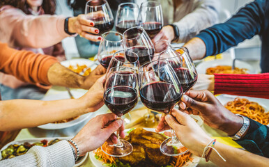 Happy friends toasting red wine glasses at dinner party - Group of people having lunch break at bar restaurant - Life style concept with guys and girls hanging out together - Food and beverage