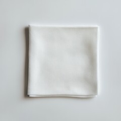 A simple white cloth napkin neatly folded on a light surface.