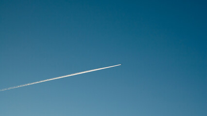blue background, in the photo blue sky and white line from the flying plane