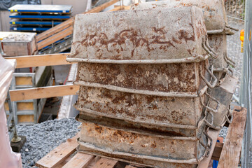 Concrete and mortar troughs, stacked on a wooden palette on a construction site. Troughs are rusty...