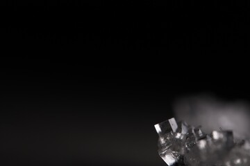 Transparent crystal on black background, minimalistic photo, place for inscription, dark copy space, salt crystals