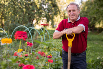 Portrait of an mature man with shovel in backyard of country house