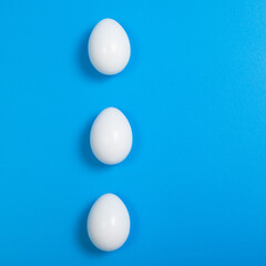 White color Eggs. Happy Easter poster, spring Christian greeting card, template sale banner, healthy menu. Bright blue color background, flat lay, copy space