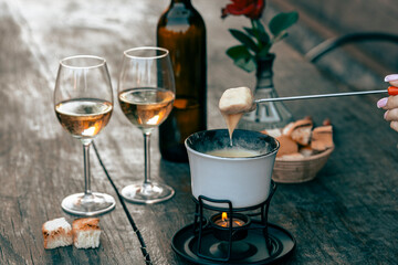 Fondue with tasty melted cheese, forks, breads and wine on wooden table, closeup