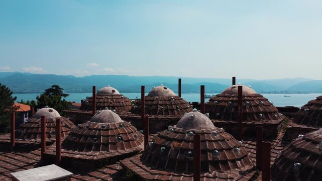 Suleyman Pasha Bath, drone scanning the domes horizontally. A natural bay in the background. Ship traffic and settlement can be seen in the sea.