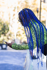 Black woman with blue hair browsing on smartphone in a city