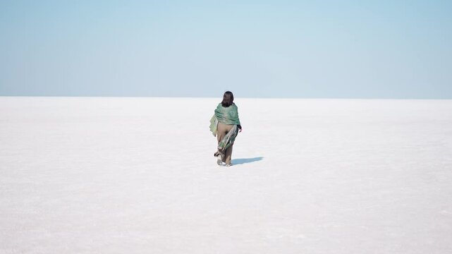 Indian girl walking at White Rann of Kutch in Gujarat, India. Tourist exploring white desert, tourism and holidays concept. Rann Utsav festival. Salt flats landscape of white desert of Kutch.