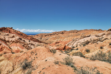 Striking landscape features expansive hills with vibrant hues of red, orange, tan, characteristic...