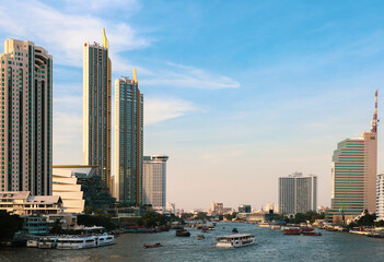 Obraz premium The blue sky of Bangkok, Thailand, viewed from the bridge over the Chao Phraya River. With busy water traffic and skyscrapers