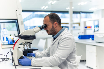 Scientist using microscope in modern laboratory performing research