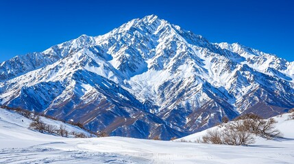 Obraz premium Majestic snow-capped mountain peak under a clear blue sky.