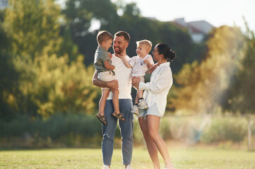 Standing together. Parents with two little sons are on the field