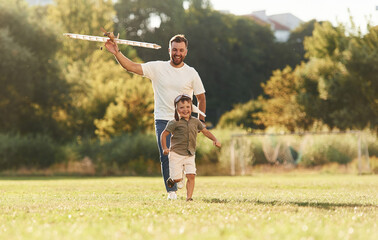 Fototapeta premium Active weekend, running. Father and son are on the field together with toy plane