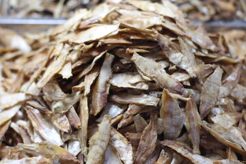 Crispy small fish placed on the stall for sale. Close up of stacked dried anchovies. A pile of dried anchovies displayed in a fish market, Little dried fish in an Asian fish market.