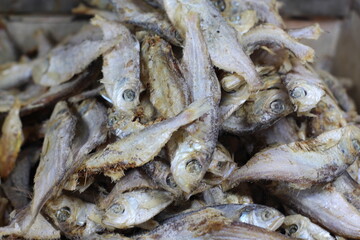 Crispy small fish placed on the stall for sale. Close up of stacked dried anchovies. A pile of dried anchovies displayed in a fish market, Little dried fish in an Asian fish market.