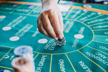 Hand placing a poker chip on a wine-themed casino game mat, blending gambling and wine culture for a unique entertainment experience