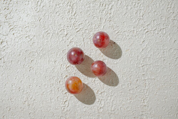 Close up of vibrant red grapes against a textured white background, highlighting their freshness and texture