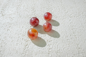 Close up of vibrant red grapes against a textured white background, highlighting their freshness and texture