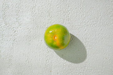 Green orange gradient citrus fruit isolated on a textured white background, showcasing its vibrant color transition