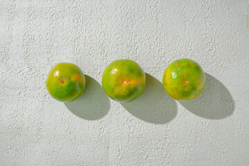 Green orange gradient citrus fruit isolated on a textured white background, showcasing its vibrant color transition