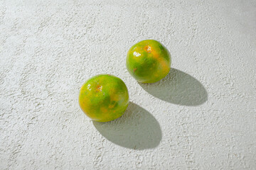 Green orange gradient citrus fruit isolated on a textured white background, showcasing its vibrant color transition