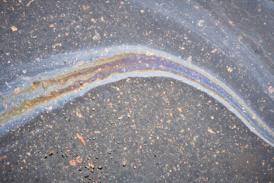 Gasoline or oil spill polluting asphalt road surface