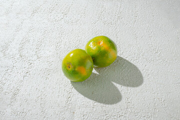Green orange gradient citrus fruit isolated on a textured white background, showcasing its vibrant color transition