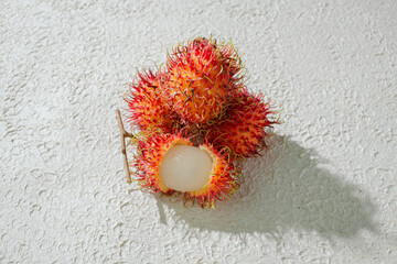 Peeled rambutan revealing its translucent, juicy flesh, set against a textured white background for...