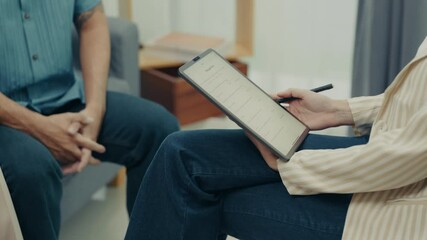 Close-up therapist reviews notes on a digital tablet while engaging with a client during a counseling session focused on relationship guidance and mental health.  
