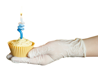 Gloved hand holding cupcake with twisted blue candle on yellow background