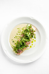 A gourmet dish featuring omelet topped with ham and fresh arugula, accompanied by a creamy sauce. Ideal for culinary and restaurant promotional materials.