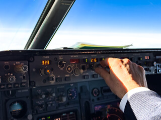 Pilot setting or adjusting autopilot in passenger airplane in flight