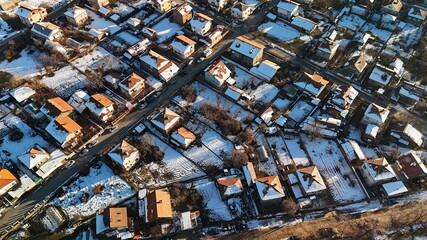 Fototapeta premium Aerial view of snowy suburban neighborhood with red roofs.