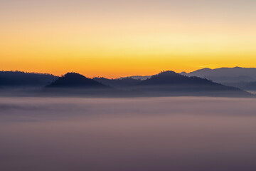 Obraz premium Mountains in clouds at sunrise in summer. mountain peak with green trees in fog.