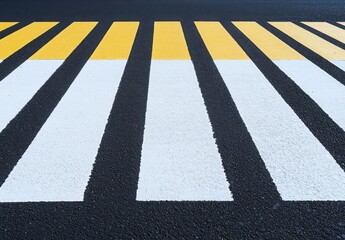 A black and white striped road with yellow lines. The road is empty