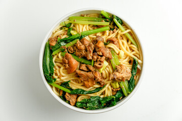 Chicken noodle or in Indonesian called mie ayam with vegetable, chopped chicken, chicken foot, isolated in white background. This food usually serve with chili or spicy red sauce