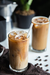 Vertical photo, Iced a coffee cup on the glass cup with roasted beans coffee and an Italian moka coffee pot on the wooden table